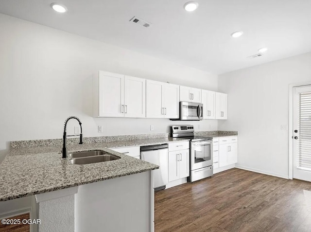 kitchen featuring a peninsula, white cabinetry, stainless steel appliances, and a sink