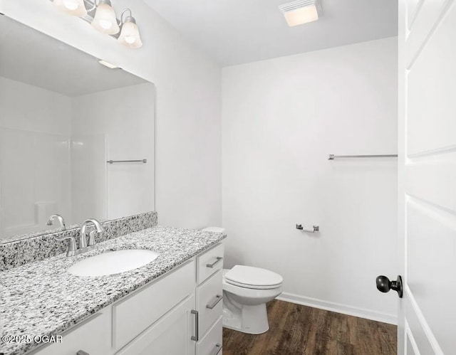 bathroom featuring toilet, baseboards, wood finished floors, and vanity