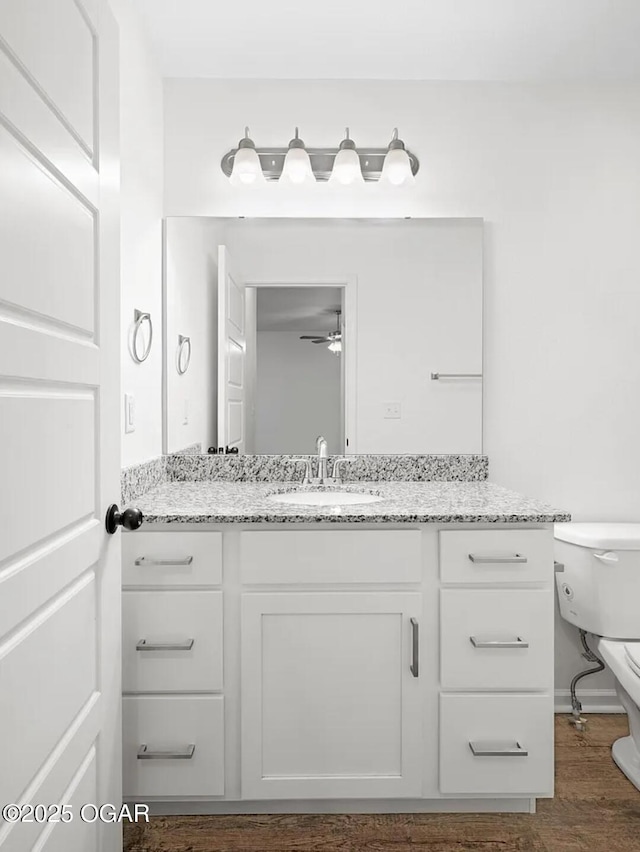 bathroom with a ceiling fan, vanity, toilet, and wood finished floors