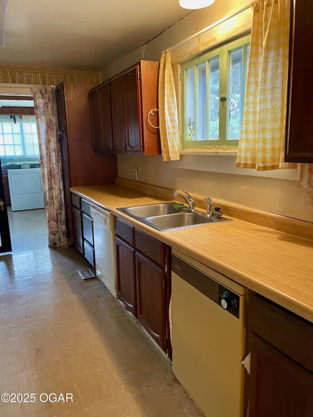 kitchen with light floors, dishwasher, washer / clothes dryer, and a sink