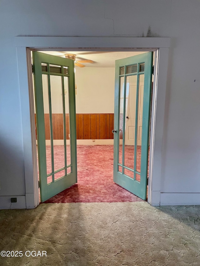 interior space with wooden walls, carpet, ceiling fan, and wainscoting