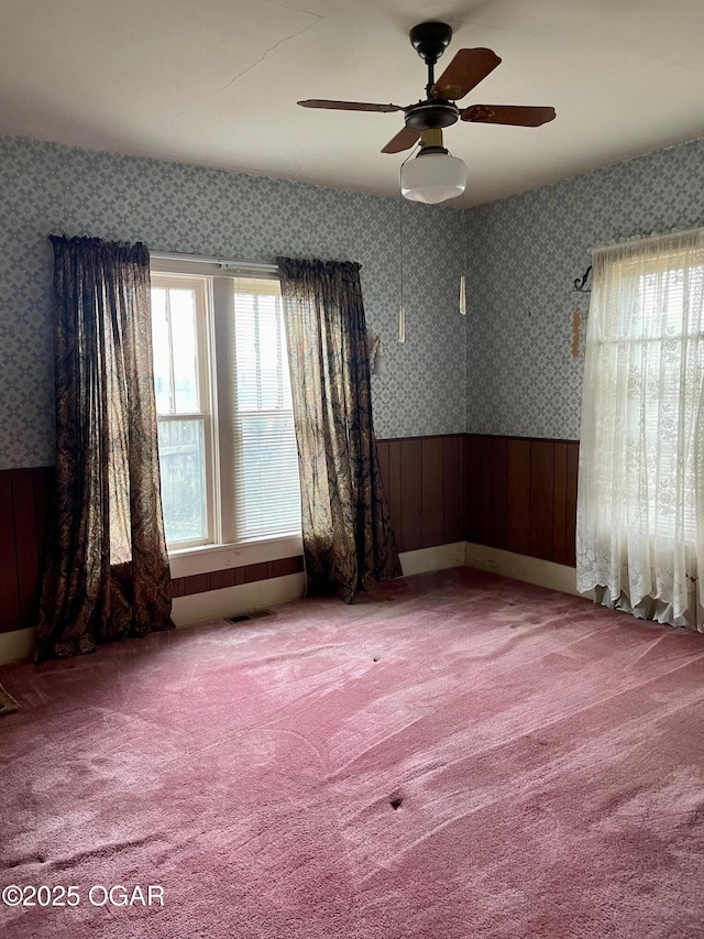 spare room with wallpapered walls, carpet, and wainscoting