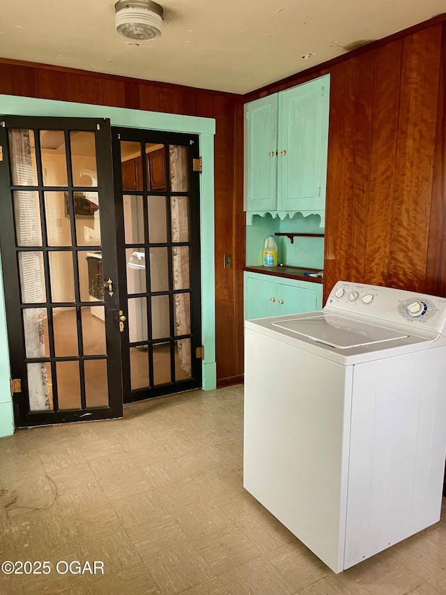 laundry area featuring wooden walls, washer / dryer, cabinet space, french doors, and tile patterned floors