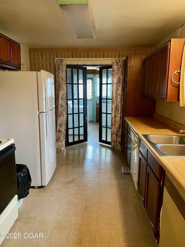 kitchen with light floors, light countertops, french doors, white appliances, and a sink