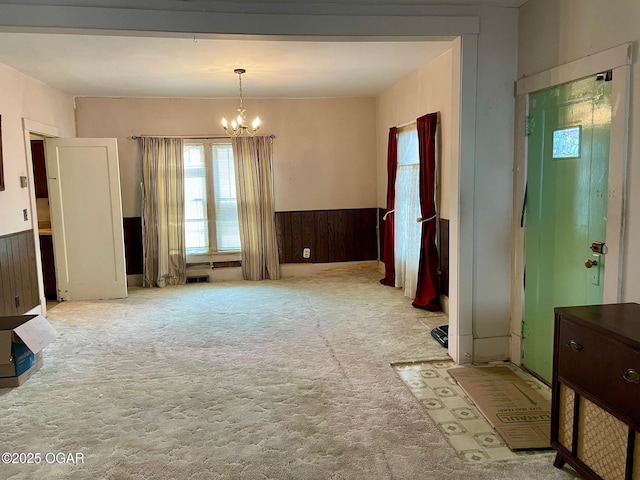 interior space featuring wooden walls, visible vents, carpet, a wainscoted wall, and a notable chandelier