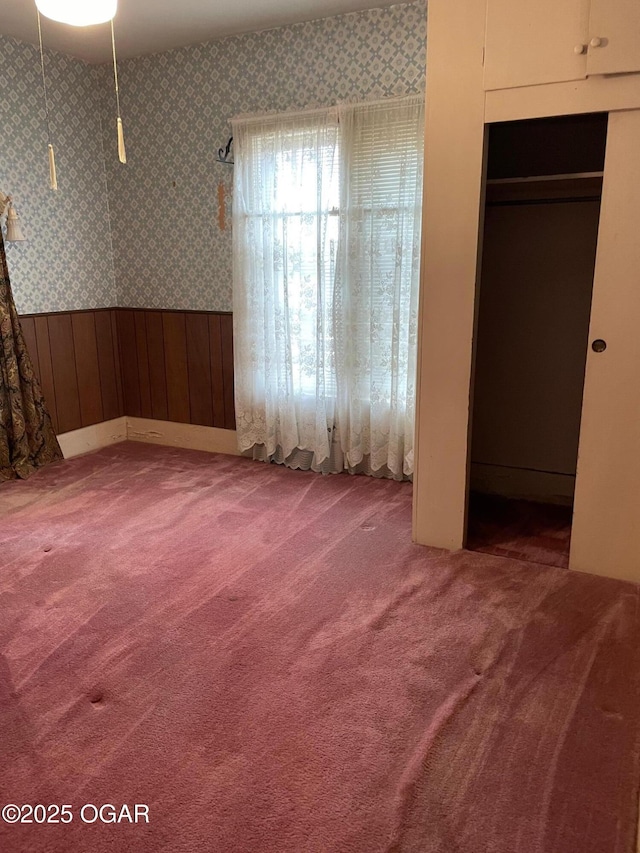 unfurnished bedroom with carpet, wainscoting, and wallpapered walls