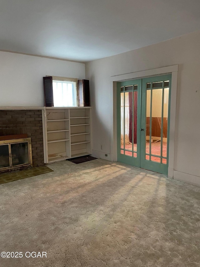 unfurnished living room featuring french doors, baseboards, and a brick fireplace