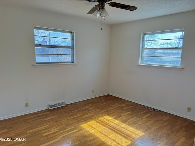 spare room with wood-type flooring, a textured ceiling, and plenty of natural light