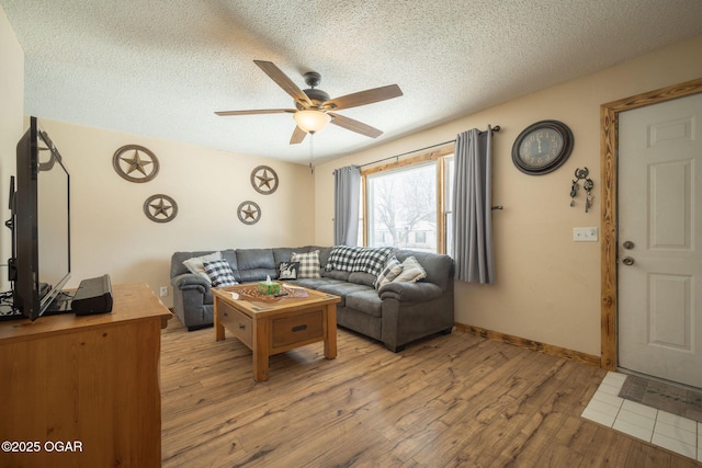 living room with ceiling fan, light hardwood / wood-style floors, and a textured ceiling