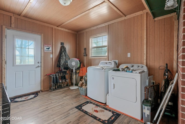 laundry area with wood-type flooring, wood walls, washer and clothes dryer, and wood ceiling