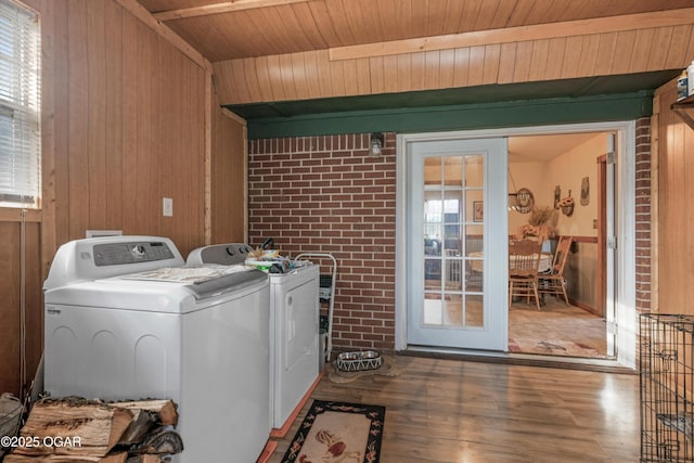 laundry room with washing machine and clothes dryer, wood-type flooring, and a healthy amount of sunlight