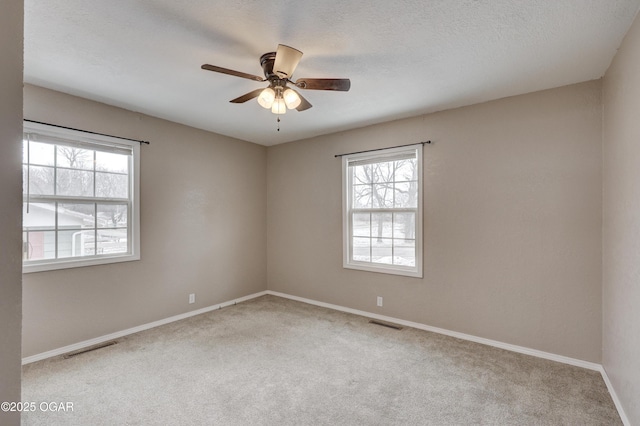 empty room with ceiling fan, a textured ceiling, and light colored carpet