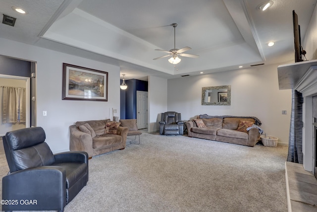 carpeted living room with a tray ceiling and ceiling fan