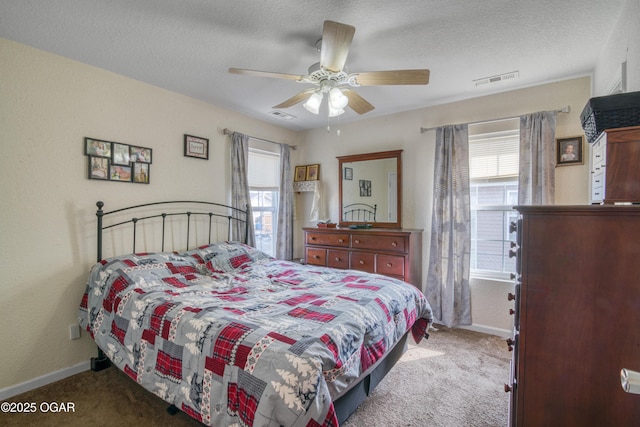 bedroom featuring baseboards, visible vents, a textured ceiling, and light colored carpet