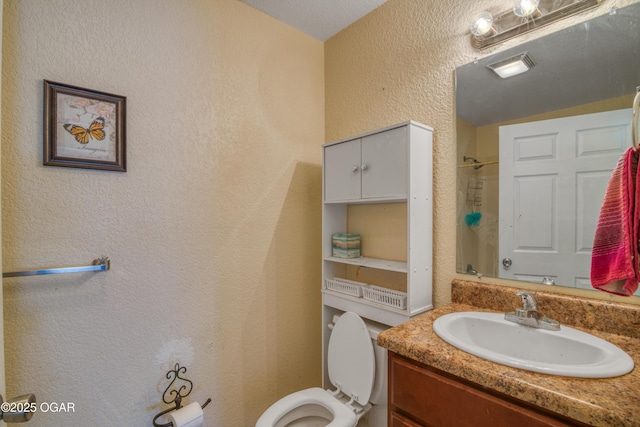 full bath with toilet, vanity, a shower, and a textured wall