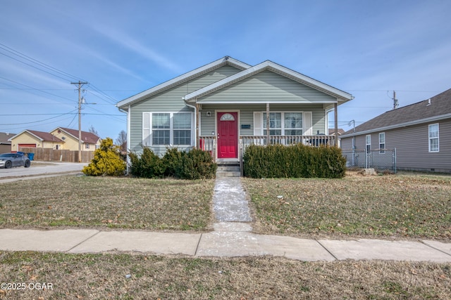 bungalow with a front yard, covered porch, and fence