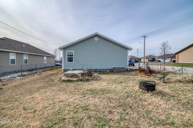 rear view of house with a fire pit, crawl space, fence, and a lawn