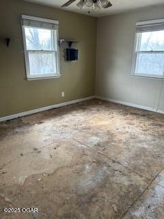 empty room with ceiling fan and baseboards