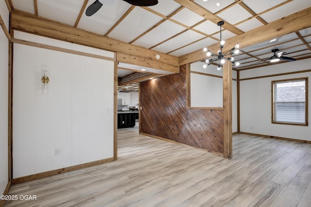 empty room with ceiling fan with notable chandelier, light wood-type flooring, beam ceiling, and baseboards