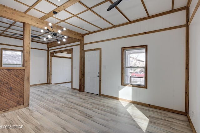 unfurnished room featuring a notable chandelier, baseboards, and light wood-style floors