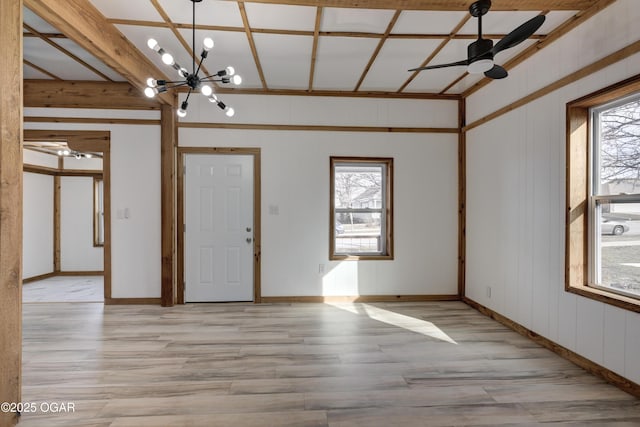 empty room with light wood-type flooring, baseboards, a wealth of natural light, and ceiling fan with notable chandelier