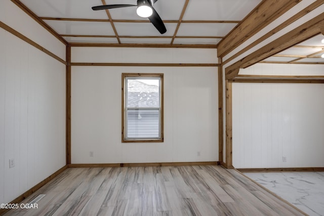 empty room with coffered ceiling, wood finished floors, a ceiling fan, and baseboards