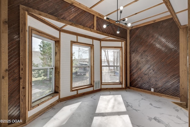 interior space with marble finish floor, baseboards, wooden walls, and a chandelier