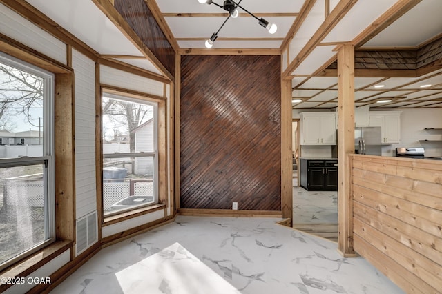 interior space featuring marble finish floor, visible vents, wooden walls, and baseboards