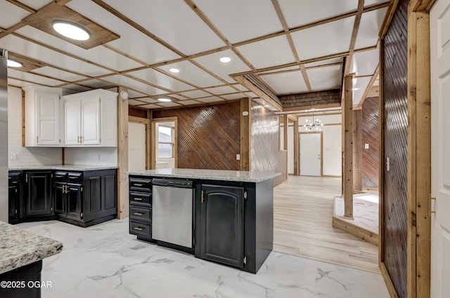 kitchen featuring refrigerator, marble finish floor, white cabinets, wooden walls, and dark cabinetry