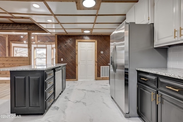 kitchen with marble finish floor, visible vents, white cabinets, wooden walls, and dark cabinets