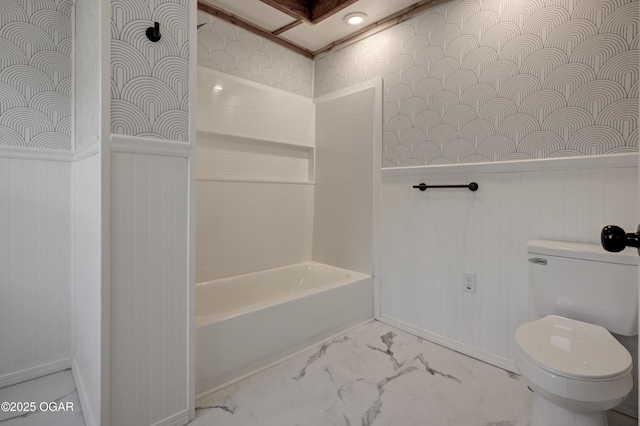 bathroom with marble finish floor, a wainscoted wall, shower / bathing tub combination, toilet, and wallpapered walls