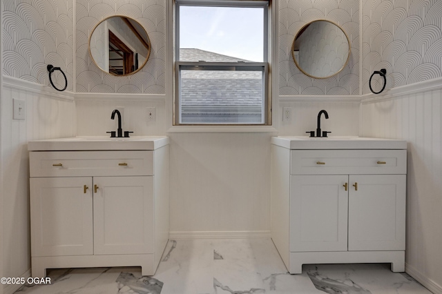 full bath featuring a sink, marble finish floor, two vanities, and wallpapered walls