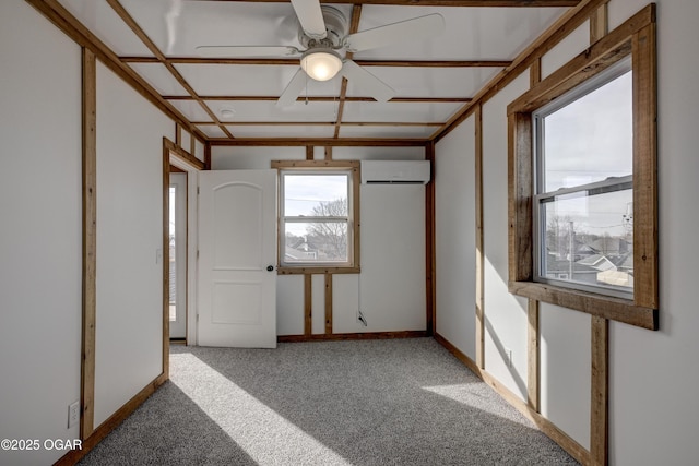 spare room with carpet floors, a wall unit AC, a ceiling fan, and baseboards