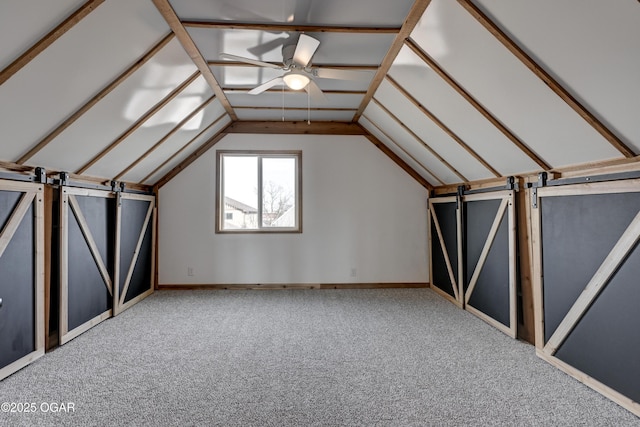 additional living space with lofted ceiling, a barn door, a ceiling fan, and carpet flooring