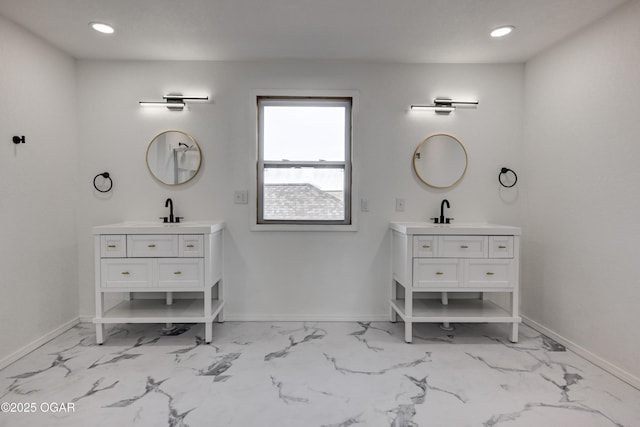 full bath with a sink, baseboards, and two vanities