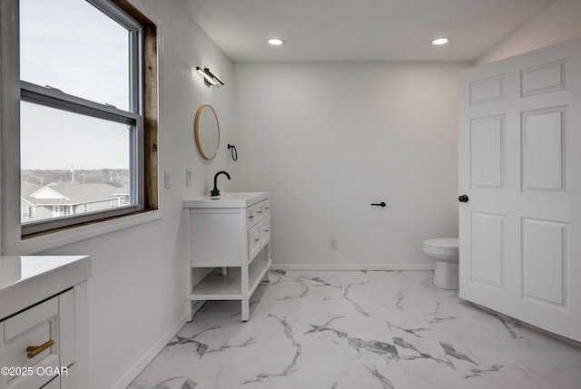 bathroom with toilet, marble finish floor, baseboards, and vanity