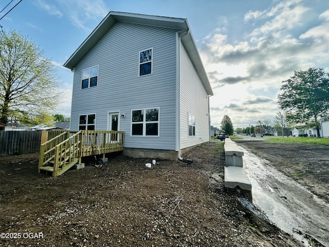 rear view of house featuring fence and a deck