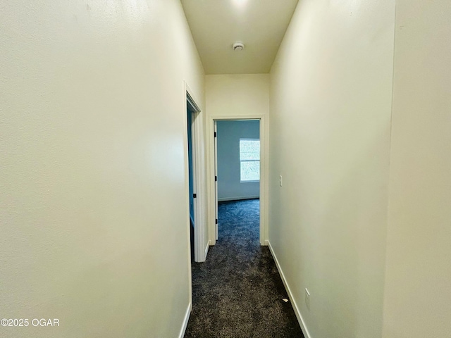 corridor with dark colored carpet and baseboards
