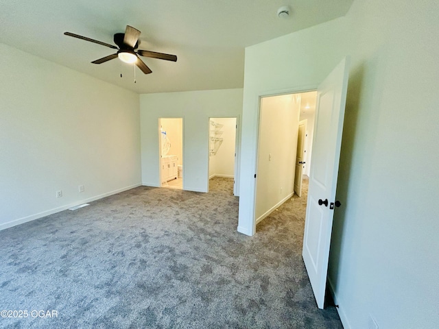unfurnished bedroom featuring baseboards, carpet flooring, and a walk in closet