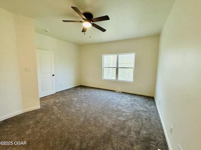unfurnished room featuring baseboards, dark carpet, visible vents, and ceiling fan
