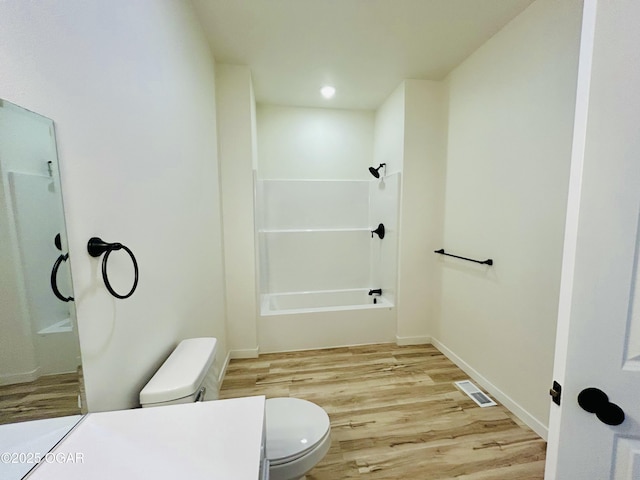 bathroom featuring toilet, baseboards, visible vents, shower / washtub combination, and wood finished floors
