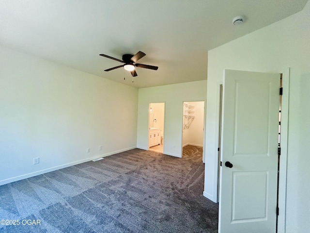 unfurnished bedroom featuring baseboards, a walk in closet, ceiling fan, and carpet floors