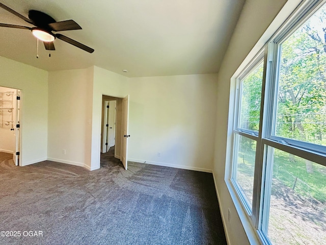 spare room featuring ceiling fan, baseboards, and dark carpet