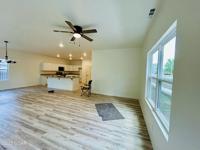 unfurnished living room with a ceiling fan, a wealth of natural light, and light wood-type flooring