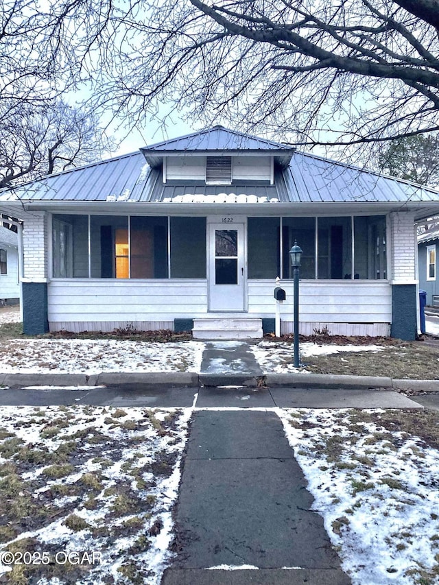 view of front facade with entry steps, metal roof, and brick siding