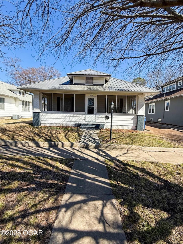 view of front of house featuring a standing seam roof, a porch, brick siding, and metal roof