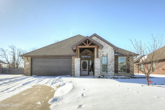 view of front of house featuring a garage, stone siding, and roof with shingles