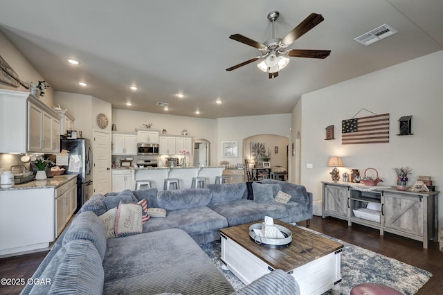 living room featuring visible vents, arched walkways, a ceiling fan, dark wood-style floors, and recessed lighting