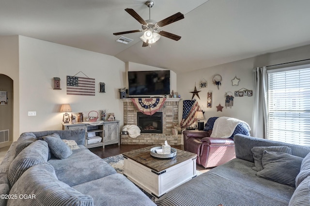 living area featuring arched walkways, a brick fireplace, lofted ceiling, and visible vents