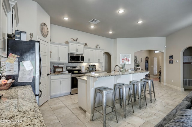 kitchen featuring appliances with stainless steel finishes, light stone countertops, visible vents, and white cabinetry